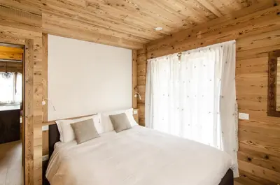 a bedroom with a white bed and a window at Casa Gerda nel cuore di Cortina d'Ampezzo in Cortina dʼAmpezzo