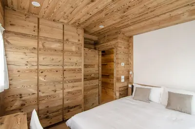 a bedroom with wooden walls and a white bed at Casa Gerda nel cuore di Cortina d'Ampezzo in Cortina dʼAmpezzo