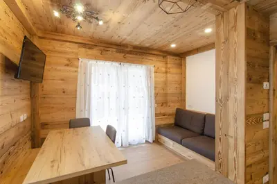 a room with a table and a couch and a window at Casa Gerda nel cuore di Cortina d'Ampezzo in Cortina dʼAmpezzo