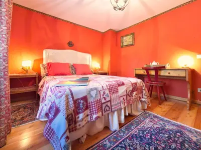 a bedroom with orange walls and a bed and a desk at Homeby, Dimora Sopiazes in Cortina dʼAmpezzo