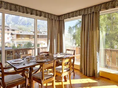 a dining room with a table and chairs and large windows at Homeby, Dimora Sopiazes in Cortina dʼAmpezzo