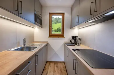 a kitchen with white cabinets and a sink and a window at Residence Peter in Ortisei