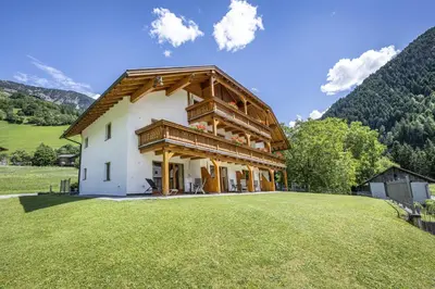 a large house with a wooden roof on a field at Residence Peter in Ortisei