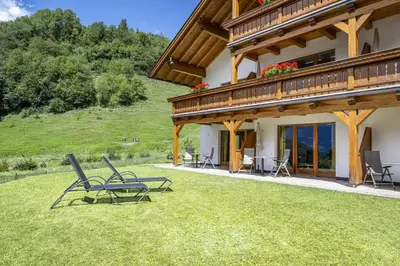 a couple of chairs sitting on the grass in front of a house at Residence Peter in Ortisei