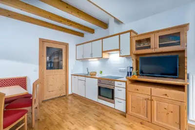 a kitchen with white cabinets and a flat screen tv at Wieserhof Vals in Valles