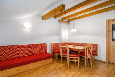 a dining room with a red couch and a table at Wieserhof Vals in Valles