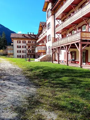 a large building with a green lawn in front of it at Aparthotel Carbonin in Dobbiaco