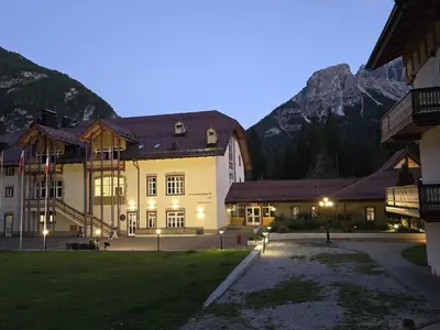 a large building with mountains in the background at Aparthotel Carbonin in Dobbiaco