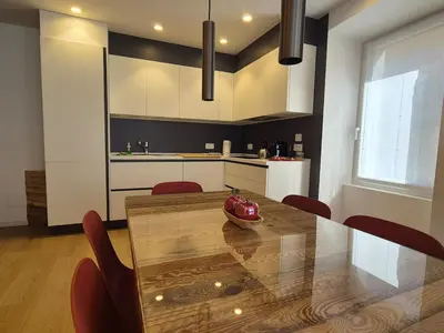 a kitchen with a dining table and red chairs at RosAlpina in Cavalese