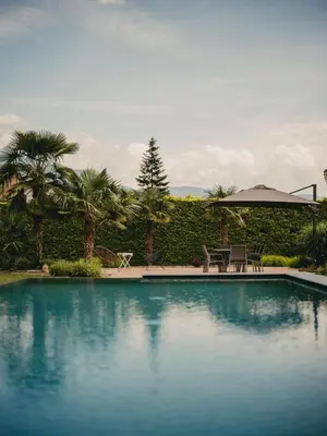 a swimming pool with two chairs and an umbrella at Luna apartments in Terlano