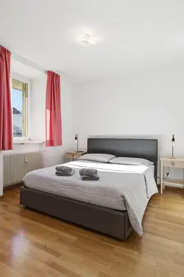 a bedroom with a large bed with red curtains at City Center Penthouse Bolzano in Bolzano
