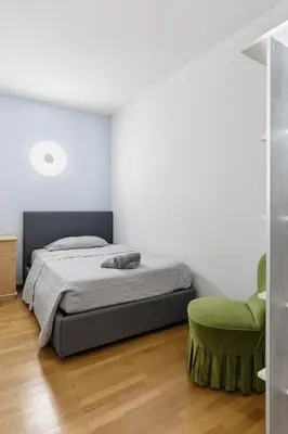 a bedroom with a bed and a green chair at City Center Penthouse Bolzano in Bolzano