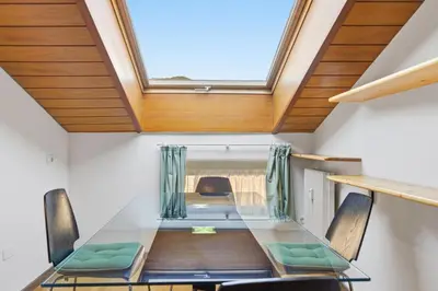 a dining room with a glass table and a skylight at City Center Penthouse Bolzano in Bolzano