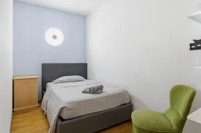 a bedroom with a bed and a green chair at City Center Penthouse Bolzano in Bolzano