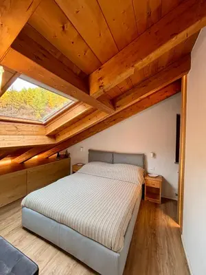 a bedroom with a bed in a room with wooden ceilings at Pragma Apartments - Sky Lodge Bellamonte in Bellamonte