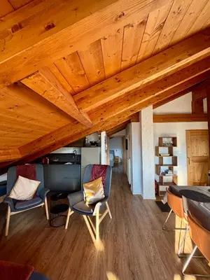 a room with wooden ceilings with chairs and a desk at Pragma Apartments - Sky Lodge Bellamonte in Bellamonte