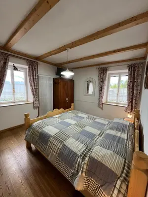 a bedroom with a large bed in a room with windows at Casa Gabry by Sunhome Fiemme in Varena