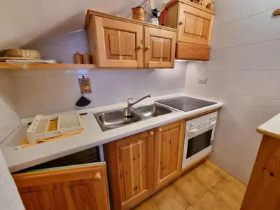 a kitchen with wooden cabinets and a sink at Villa Erica in Alba di Canazei