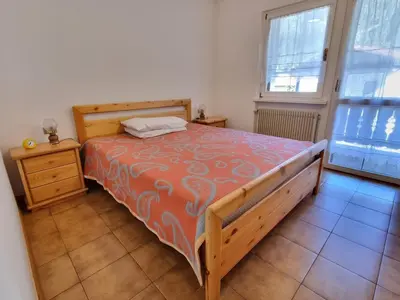a bedroom with a bed and a dresser and window at Villa Erica in Alba di Canazei