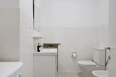 a white bathroom with a toilet and a sink at Lauben Apartment II Bolzano in Bolzano