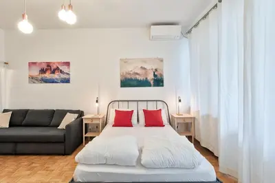 a bedroom with a bed with red pillows and a couch at Lauben Balcony Bolzano in Bolzano