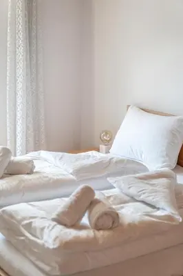 a bed with white sheets and towels on it at Apartments Palma in Cortaccia