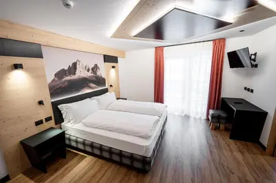 a bedroom with a bed and a large window at Albergo Garni Edy (B&B) in Canazei