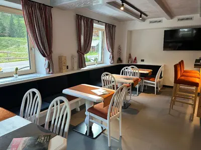 a dining room with two tables and chairs and windows at Albergo Garni Edy (B&B) in Canazei