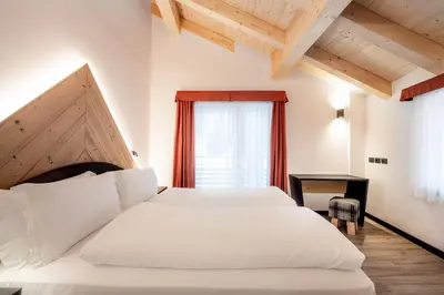 a bedroom with a large white bed and a window at Albergo Garni Edy (B&B) in Canazei