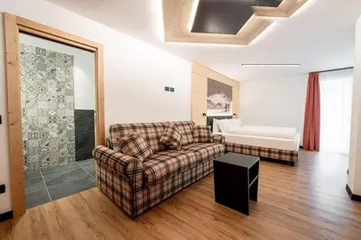 a living room with a couch and a bed at Albergo Garni Edy (B&B) in Canazei
