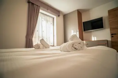 a bedroom with a bed and a large window at La Stua de Anny by AMA Val di Fassa in Pozza di Fassa