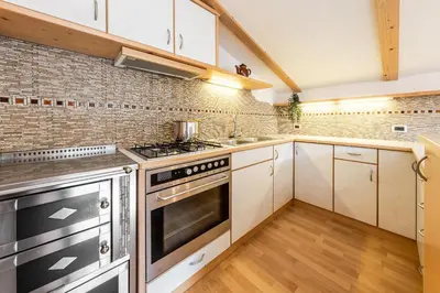 a kitchen with stainless steel appliances and a brick wall at Ciasa Miriam in La Valle