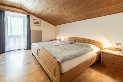 a bedroom with a wooden bed and a large window at Ciasa Miriam in La Valle