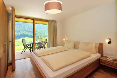 a bedroom with a large bed and a balcony at Peterwieshof in Funes
