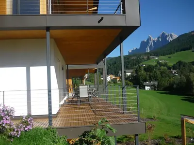a house with a balcony with mountains in the background at Peterwieshof in Funes