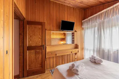 a bedroom with a bed with a tv and a window at Casa Fior di Ghiaccio in Cortina dʼAmpezzo