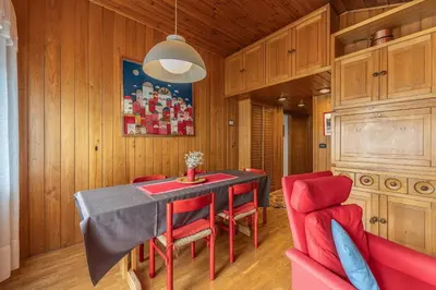 a dining room with a table and red chairs at Casa Fior di Ghiaccio in Cortina dʼAmpezzo