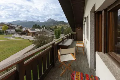 a balcony with a chair and a view of the mountains at Casa Fior di Ghiaccio in Cortina dʼAmpezzo