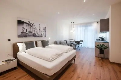 a bedroom with a large bed and a dining room at ecHo Apartments & SPA in Bressanone