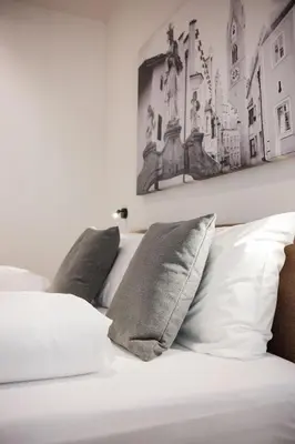 a bedroom with a bed with white sheets and pillows at ecHo Apartments & SPA in Bressanone