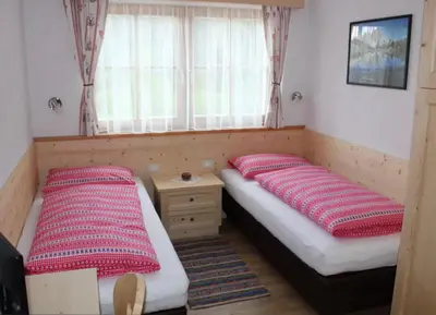 two twin beds in a room with a window at Appartamenti Chantal in San Martino in Badia
