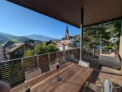 a wooden table on a balcony with a view of a city at Oase mit Fernblick in Mühlbach