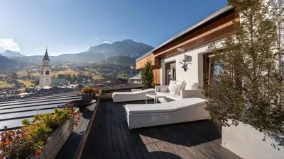 a balcony with couches and a view of a city at Chalet Fenice by My Villa Collection in Cortina dʼAmpezzo