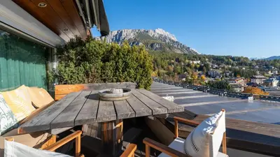 a wooden table on a balcony with a view of a mountain at Chalet Fenice by My Villa Collection in Cortina dʼAmpezzo
