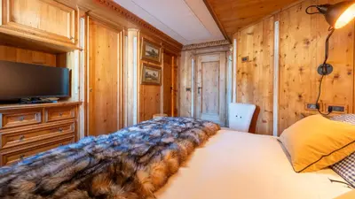 a bedroom with a bed and a tv and wooden walls at Chalet Fenice by My Villa Collection in Cortina dʼAmpezzo
