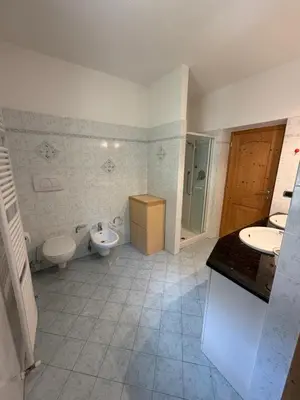 a bedroom with a bed and a table and cabinets at Casa Lilla Predazzo in Predazzo