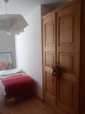 a bedroom with a wooden door and a red bed at Casa Lilium in Daiano