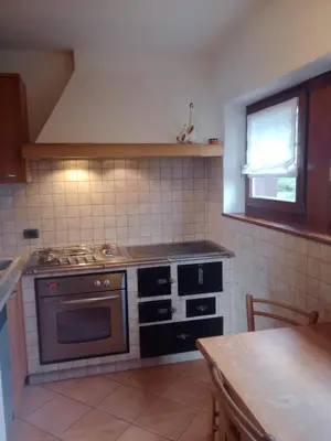 a kitchen with a stove and a sink and a table at Casa Lilium in Daiano