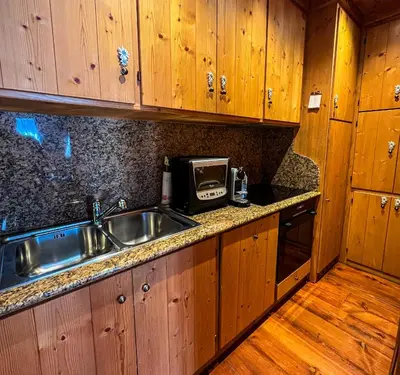 a kitchen with a sink and a microwave at Cortina Wood Home - a short walk from the center in Cortina dʼAmpezzo