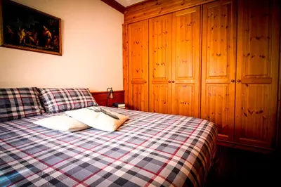 a bedroom with a bed with a checkered blanket at Cortina Wood Home - a short walk from the center in Cortina dʼAmpezzo